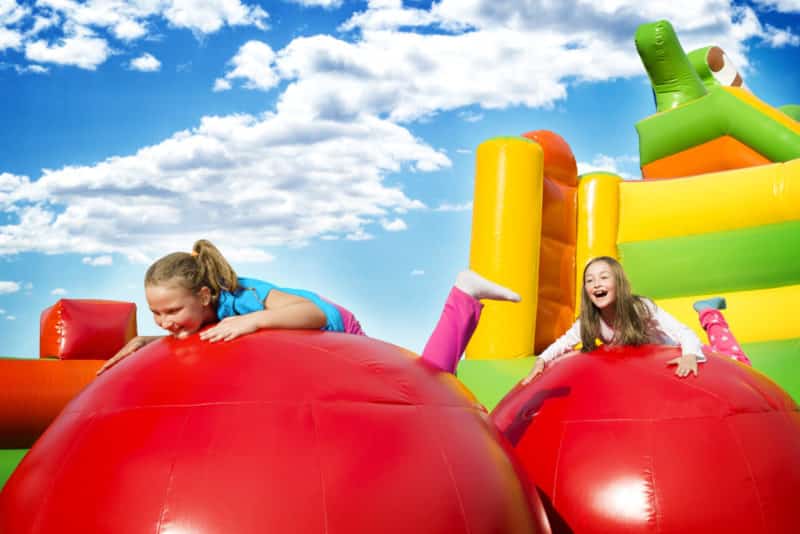 Happy little girls having lots of fun while jumping from ball to ball on an inflate castle | Australian Inflatables